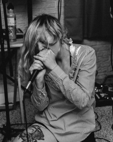 Female singer kneeling, clutching microhpone.